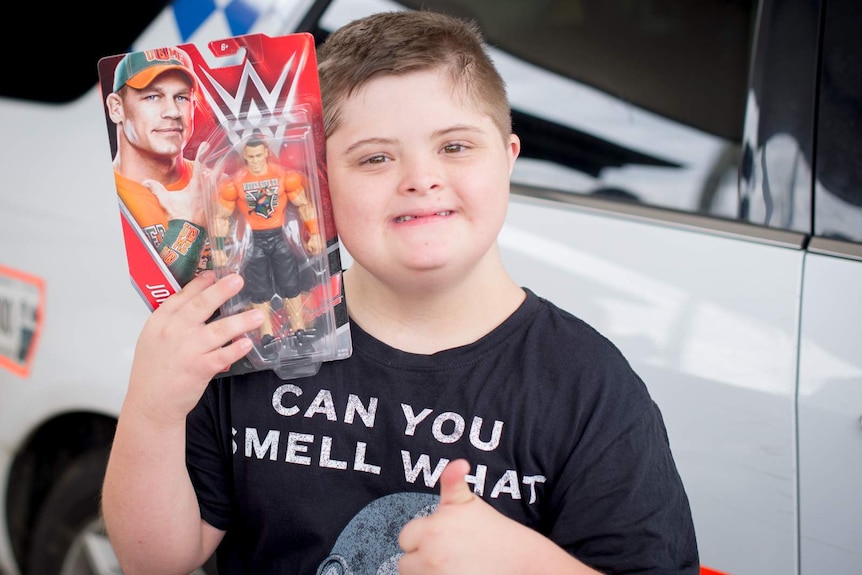 Jesse Fullerton gives a thumbs up as he holds on to a brand new wrestling figurine donated by toy manufacturer Mattel.