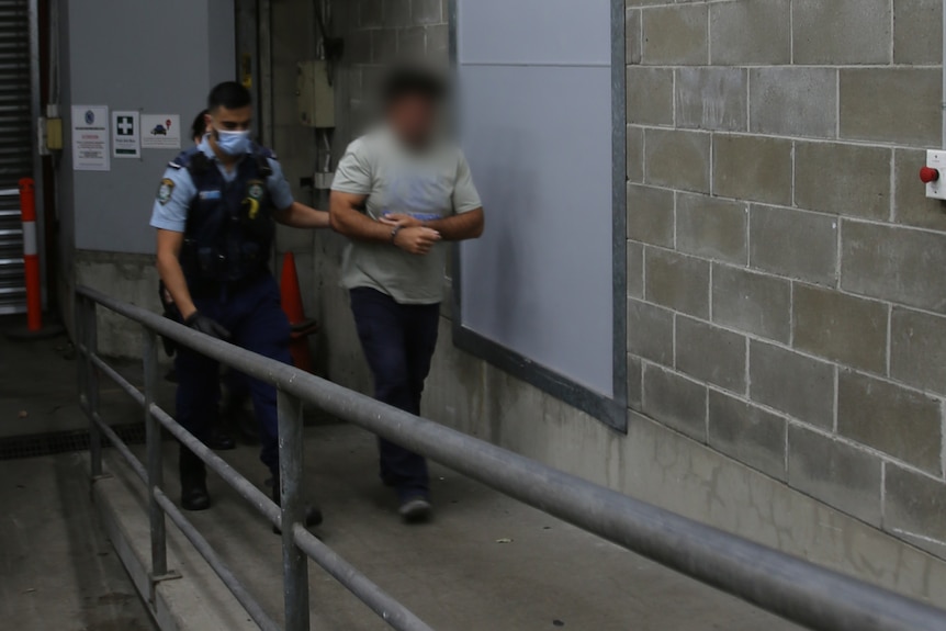 A police officer leads a man inside a police station