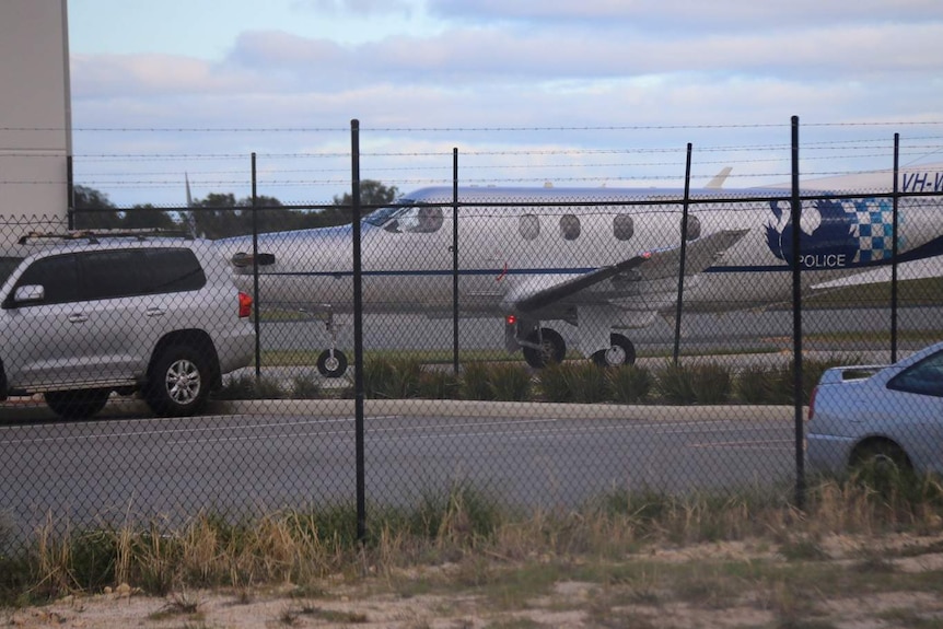 Brenden Abbott's plane arrives in Jandakot, Perth, seen through chain link fence.