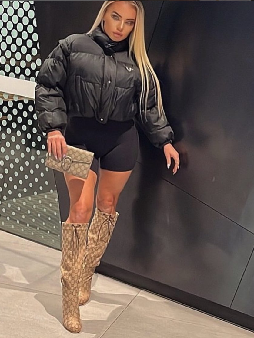 A woman wearing a black puffer jacket with long blonde hair and knee-high boots