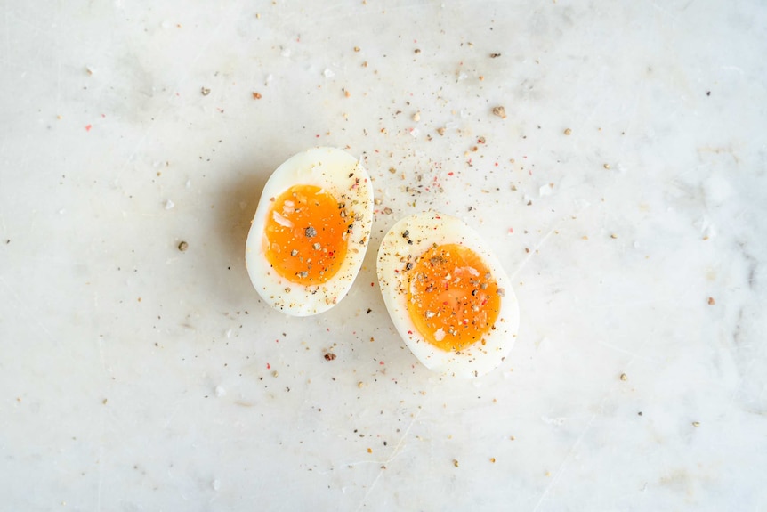 A soft boiled egg sliced in half and dusted with seasoning, some eggs are easier to peel than others.