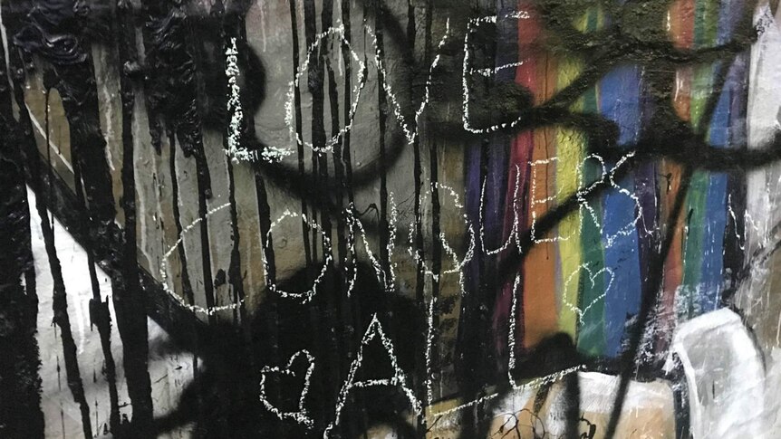 The words "Love conquers all" can be seen on a mural.