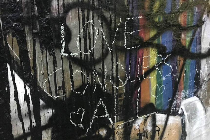 The words "Love conquers all" can be seen on a mural.