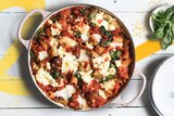A pan filled with baked tomato pasta topped with cheese and spinach to depict recipes using pantry staples like pasta and beans.