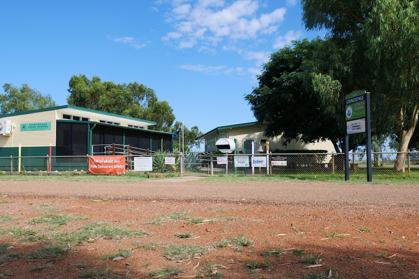 The street view of the Stonehenge State School. Red dirt entryway and two main buildings. 