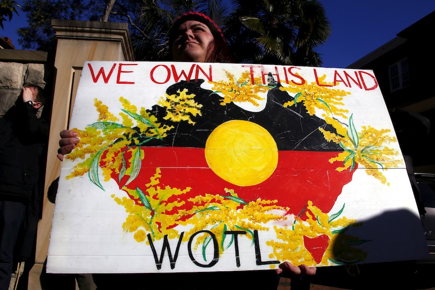 以原住民旗帜填充的澳大利亚地图被金色合欢花包围