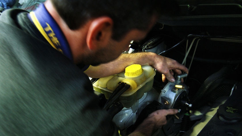 A mechanic works on a car engine.