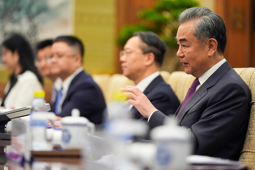 China's foreign minister sitting at a table with others during a meeting.