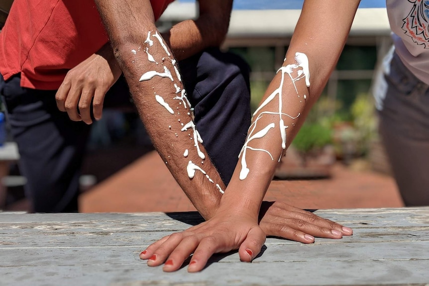 Soumia and Nakul wearing sunscreen on their arms for story about sunscreen and darker skin