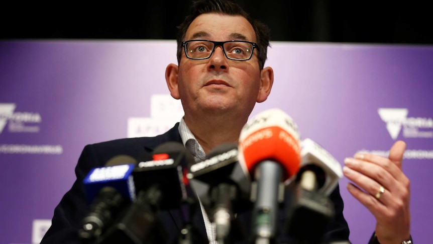 Daniel Andrews speaks to media at a press conferences with microphones in front of him
