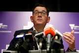 Daniel Andrews speaks to media at a press conferences with microphones in front of him