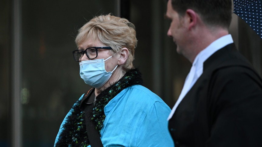 A woman wearing a blue face mask and a blue shirt and glasses.