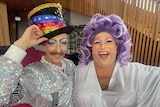 Two drag performers, one in a top-hat with moustache and another in a purple wig