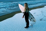 A teenage girl looks out over the water from a snow-covered beach south of Hobart in 2015