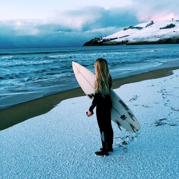 A teenage girl looks out over the water from a snow-covered beach south of Hobart in 2015