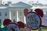Protest signs demanding climate change action are held up in front of the White House