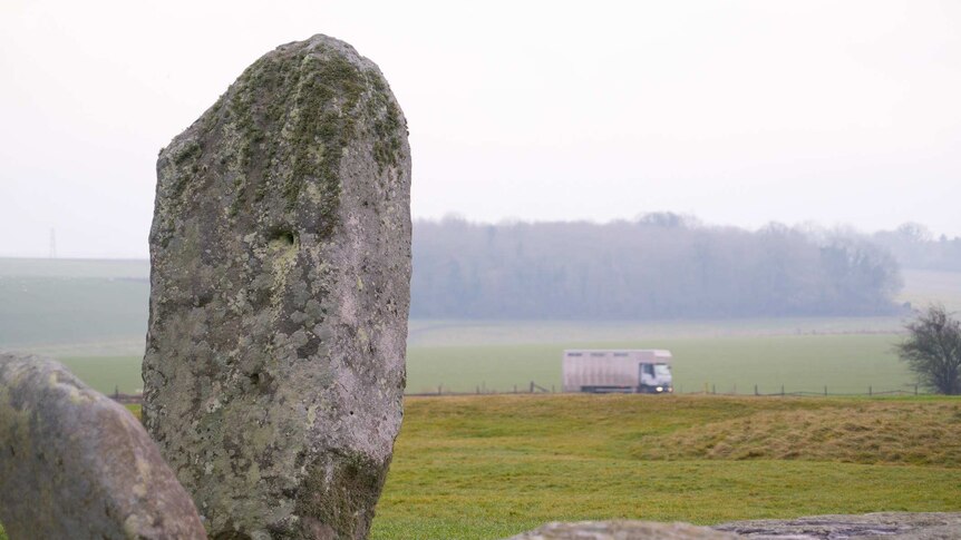 A van passes by the 5000-year-old Stonehenge monument on a nearby road.