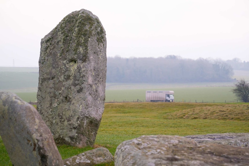 A van passes by the 4000-year-old Stonehenge monument on a nearby road.