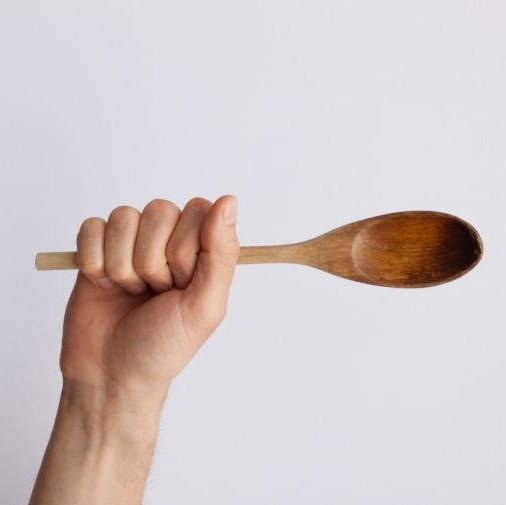 Hand holding wooden spoon.