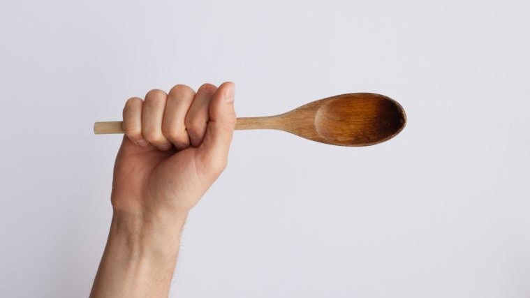 Hand holding wooden spoon.