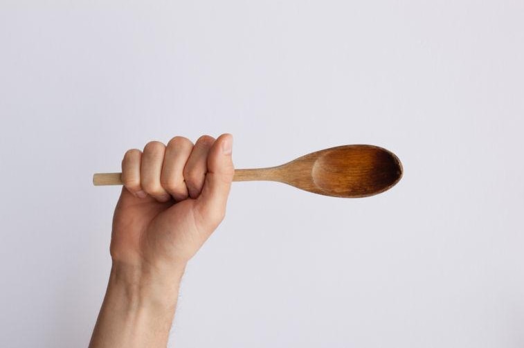 Hand holding wooden spoon.