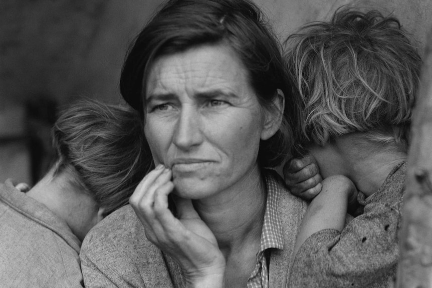 An old black and white photo of a mother during the Great Depression holding her children