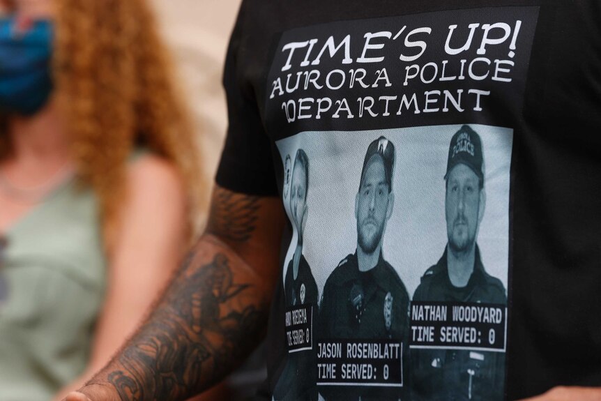 A man wears a black shirt bearing photographs of three Aurora policeman.