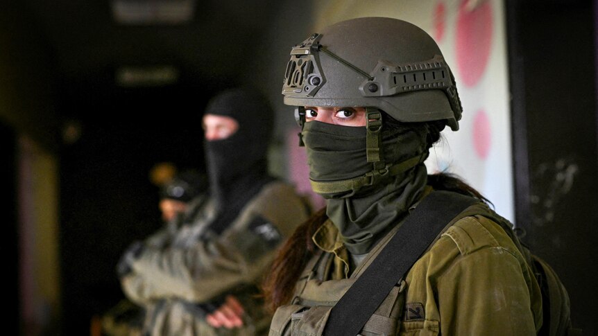 A female soldier in a helmet and face covering 