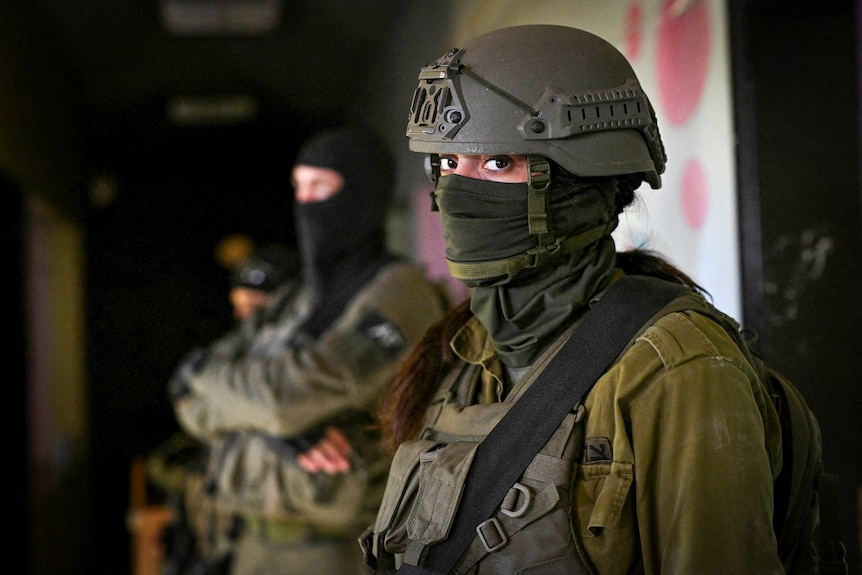 A female soldier in a helmet and face covering 