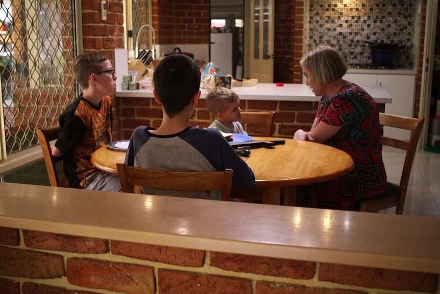 Melissa Rowles sitting at a dining table with her three sons