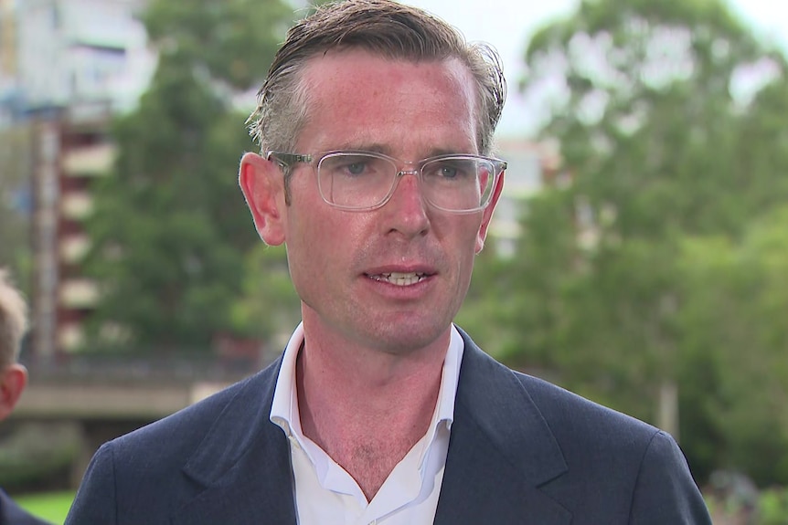 a man wearing glasses standing outdoors talking