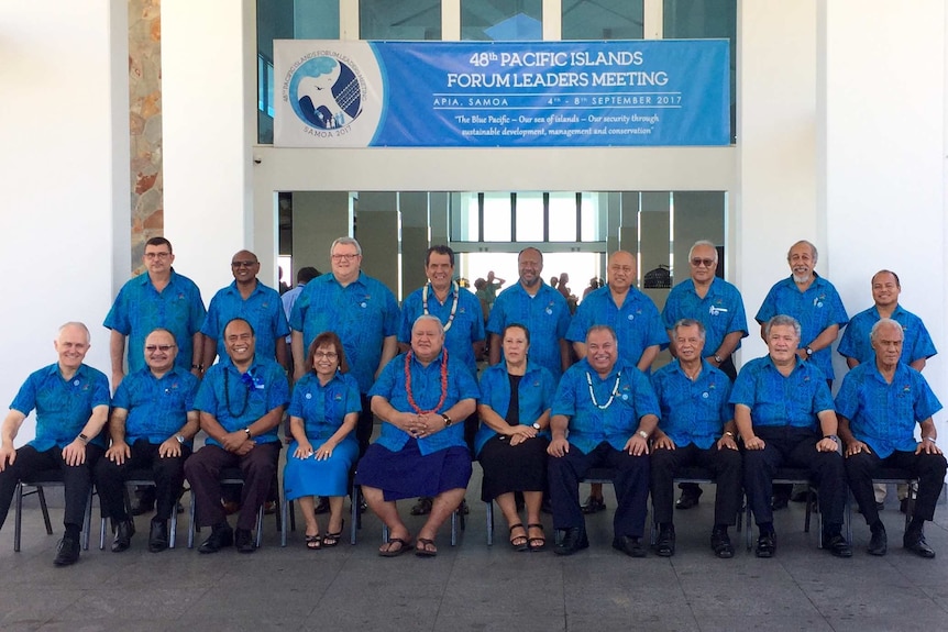 A group of world leaders dressed in blue shirts pose for a group photo. Malcolm Turnbull is seated on the left.