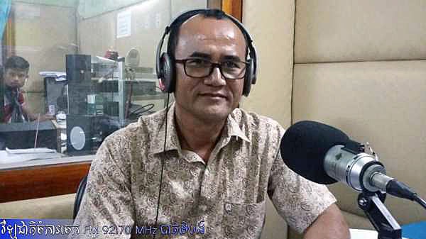 Presenter sitting at microphone of Battambang's provincial department of innovation radio station in Cambodia