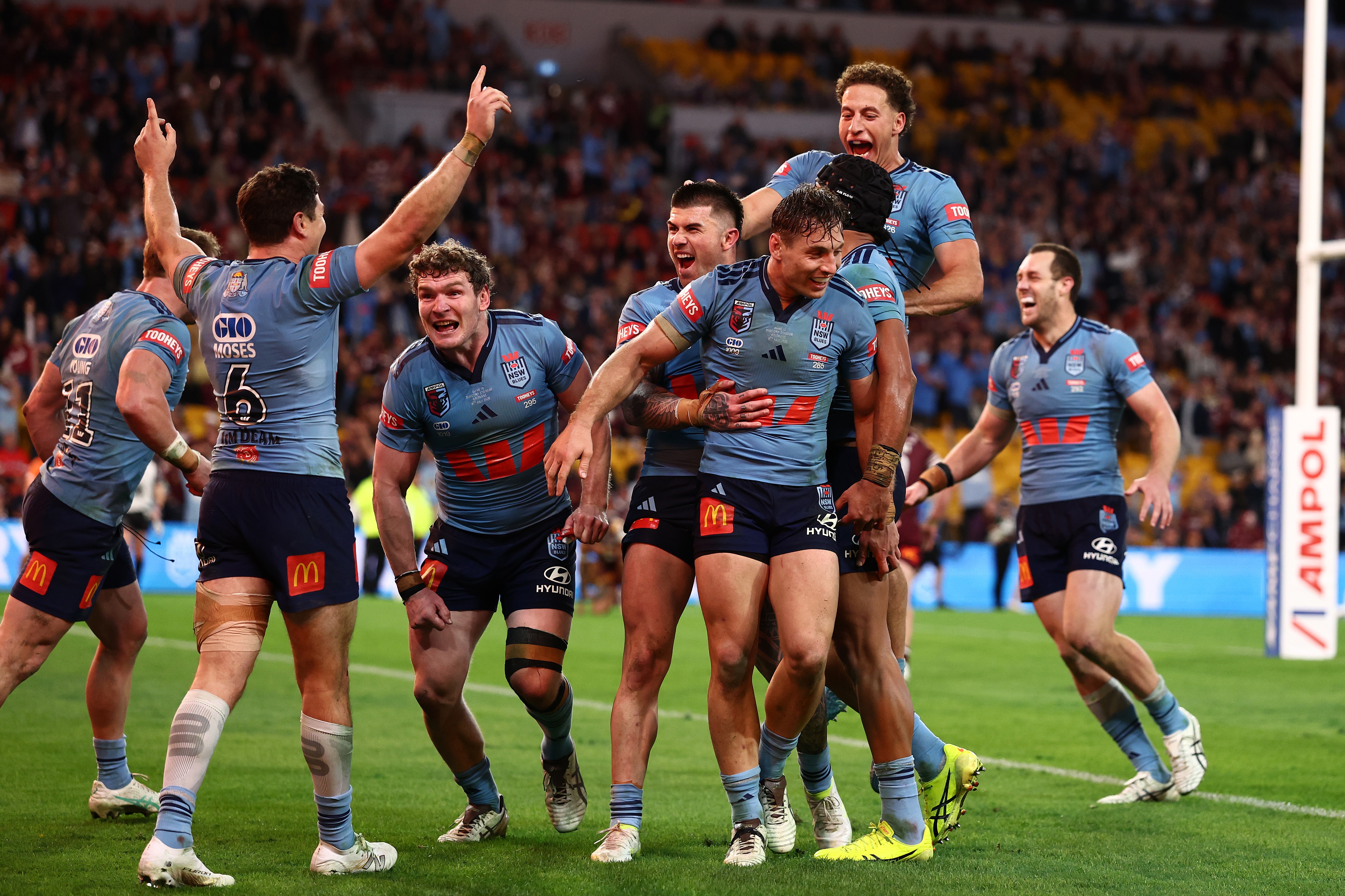 A group of rugby league players in blue celebrate a victory