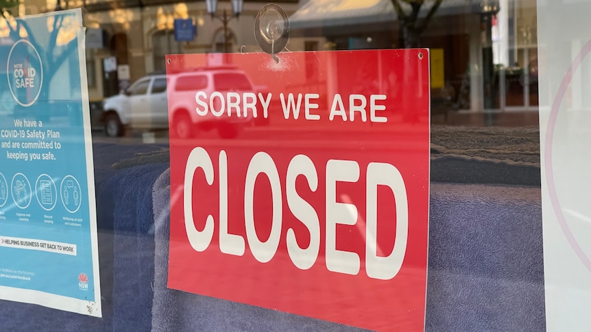 A red sign on a  glass window reads sorry we're closed