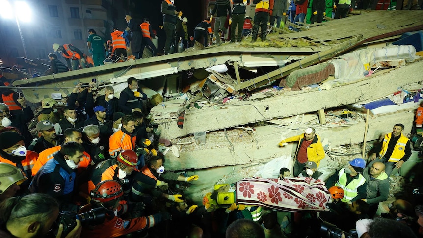 Rescue workers carry a woman from the rubble of an eight-story building which collapsed in Istanbul.