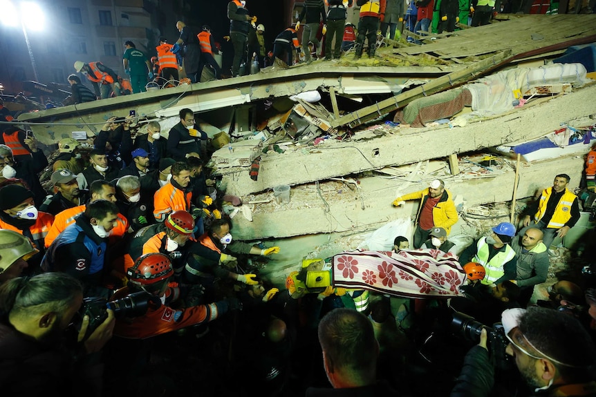 Rescue workers carry a woman from the rubble of an eight-story building which collapsed in Istanbul.