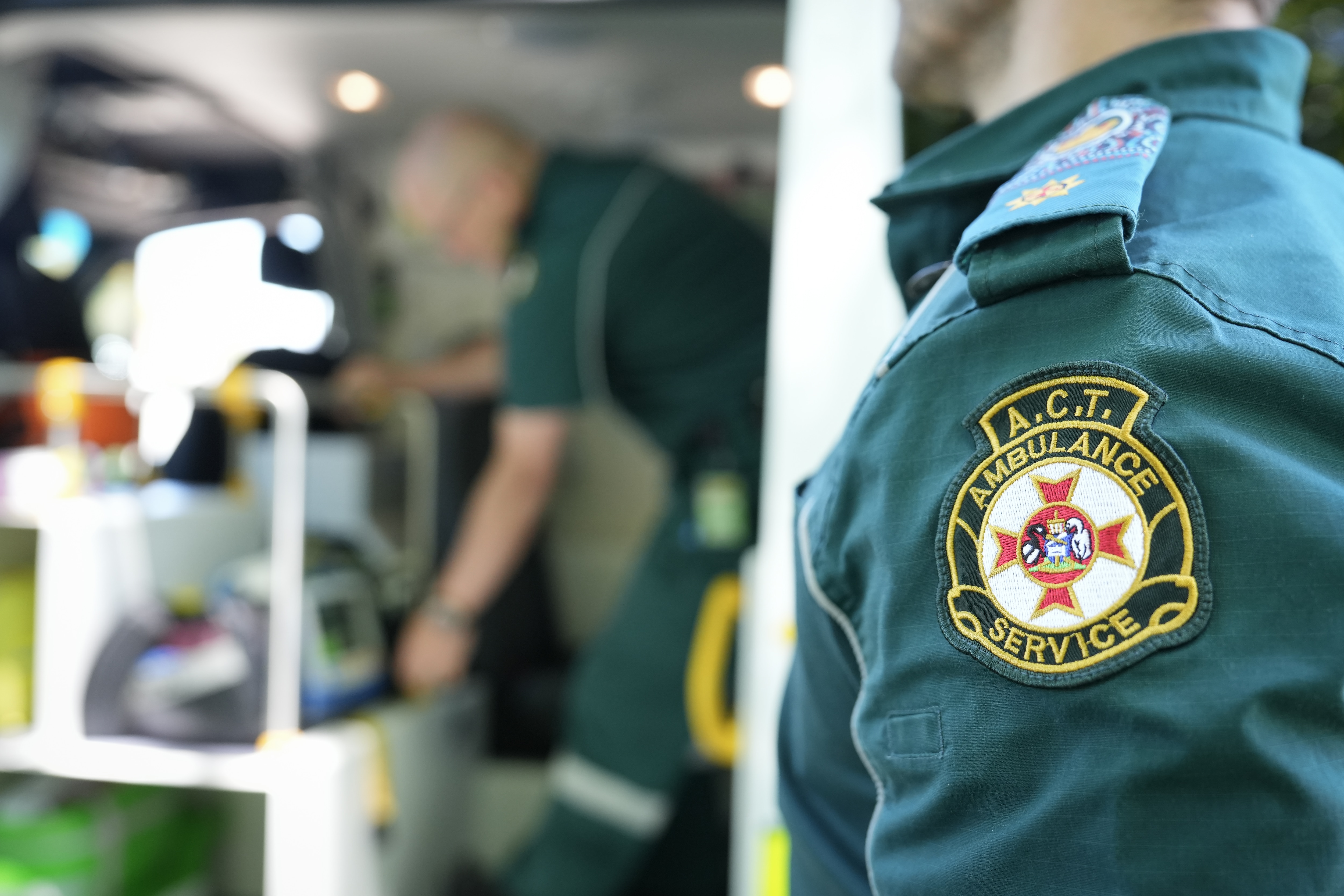A uniformed paramedic looking into the open back doors of an ambulance.
