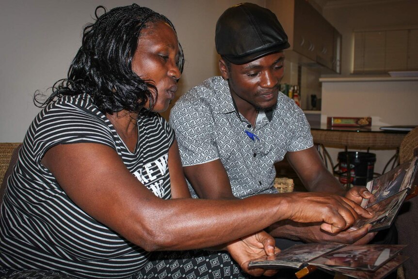Pascasia Nyirashaka and her son Dennis Bemeliki looking at a photo album from their lives in Africa.