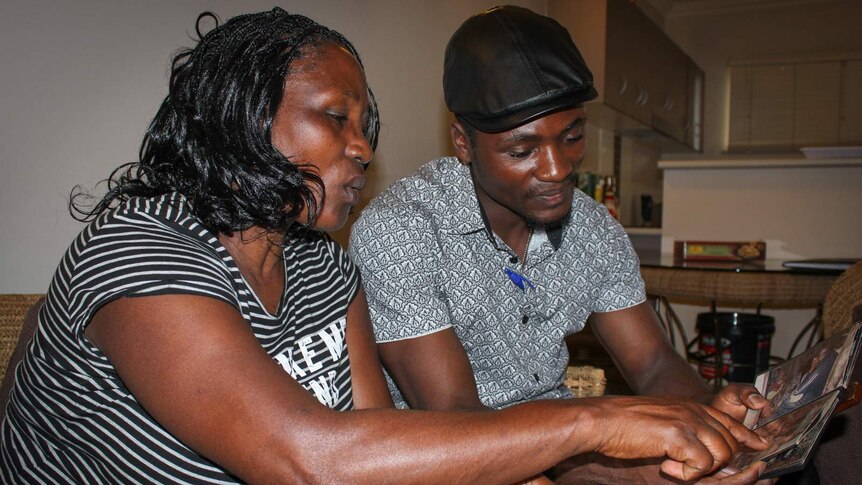 Pascasia Nyirashaka and her son Dennis Bemeliki looking at a photo album from their lives in Africa.