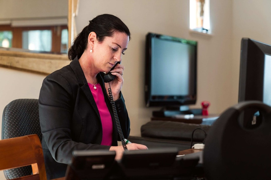 Chartered Accountant Lisel Montague  sits at a desk talking on a landline telephone.