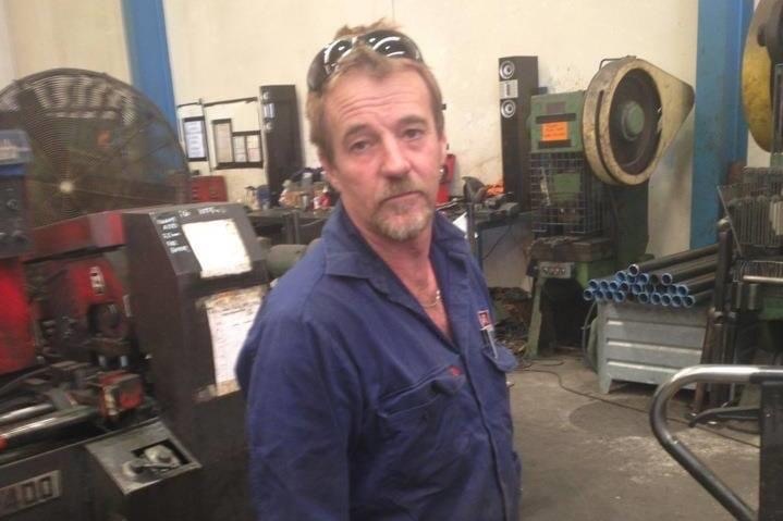 David Best wearing navy blue work clothes in a mechanic shed.