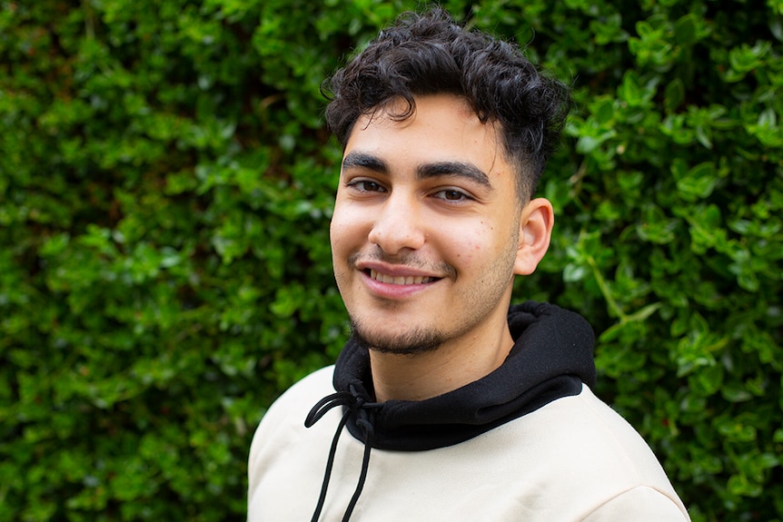 A young man wearing a hoodie smiles