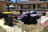 Furniture and rubbish bins fill the front yard of an abandoned home in the western Sydney suburb of Bidwill.