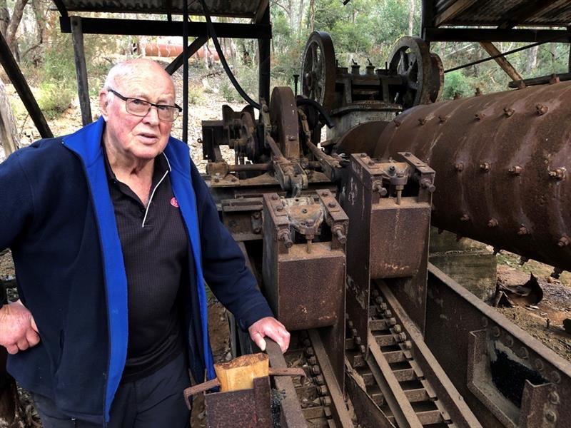 Photo of a man standing next to a gold mine relic.