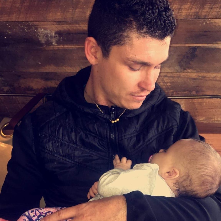 Marcus Rowley holding his baby daughter.