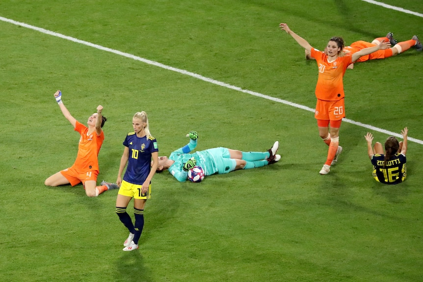 Dutch players fall to the ground in delight as the full-time whistle blows.