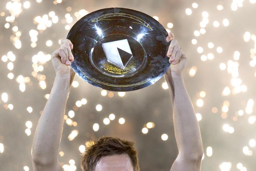 Robin Soderling lifts a plate-style trophy as sparks fly behind him.