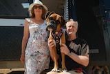 A boxer dog and her owners outside of a caravan