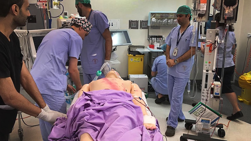 Doctors and nurses standing over a mannequin, learning about the new blood machine.